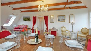 Un coin repas avec une table en bois dressée pour le repas, un lustre et des meubles classiques.