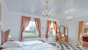 Ein Hotelzimmer mit Schachbrettfußboden, einem Bett, einem Schminktisch, einem Spiegel und einer Chandelier.
