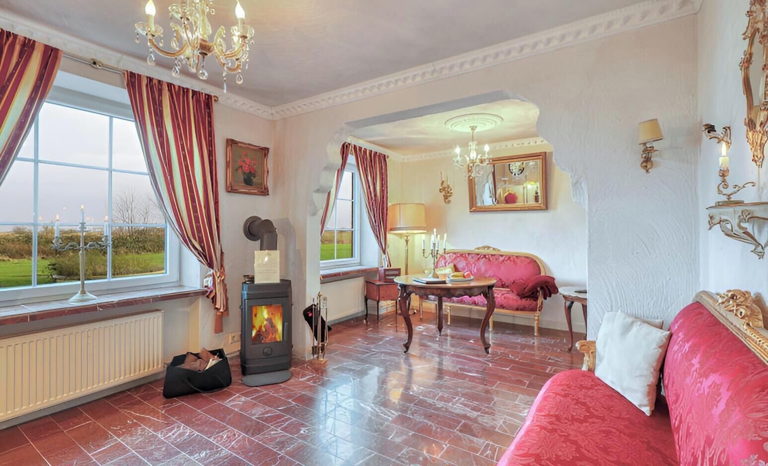 A room with a fireplace, a sofa, a table, and a window with curtains.