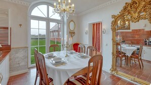 A dining room with a large table set for six, a chandelier, and a view of the outdoors.