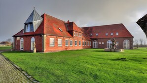 A large brick building with a prominent tower, a fountain, and a well-maintained lawn.
