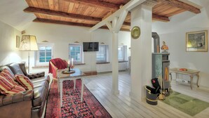A living room with a leather sofa, a patterned rug, a fireplace, and a television. - Apartment 'Junior Suite' with Shared Garden and Wi-Fi (Emmelsbüll-Horsbüll)