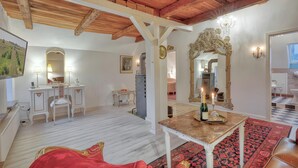 A hotel room with a wooden ceiling, a large mirror, a small table with a bottle, a red sofa, and a patterned rug. - Apartment 'Junior Suite' with Shared Garden and Wi-Fi (Emmelsbüll-Horsbüll)