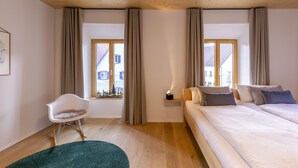 A modern hotel room with a wooden ceiling, two beds, a chair, a small table, and a window with curtains. - Apartment 'Anna' with Shared Terrace, Balcony and Wi-Fi (Elzach)