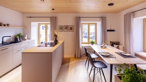 A modern kitchen with a central island, a dining area with a long table, and large windows with curtains. - Apartment 'Anna' with Shared Terrace, Balcony and Wi-Fi (Elzach)
