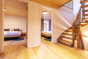 Ein modernes Interieur mit Holzböden, einer Treppe und zwei Schlafzimmern mit Betten.