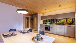 A modern kitchen with a built-in fish tank, wooden ceiling, and a dining area with a table set for two.