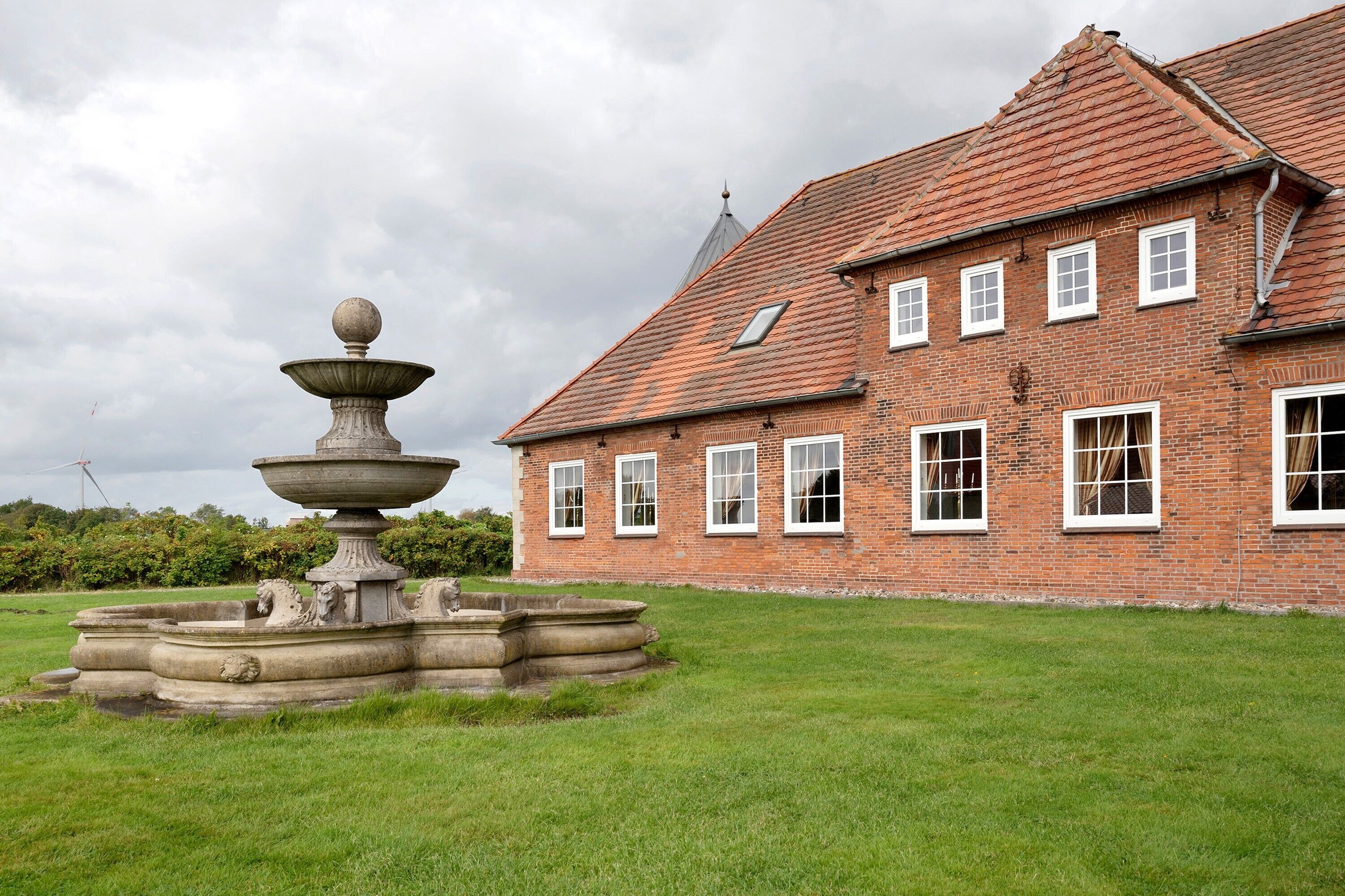 Un grand bâtiment en briques avec une fontaine devant.