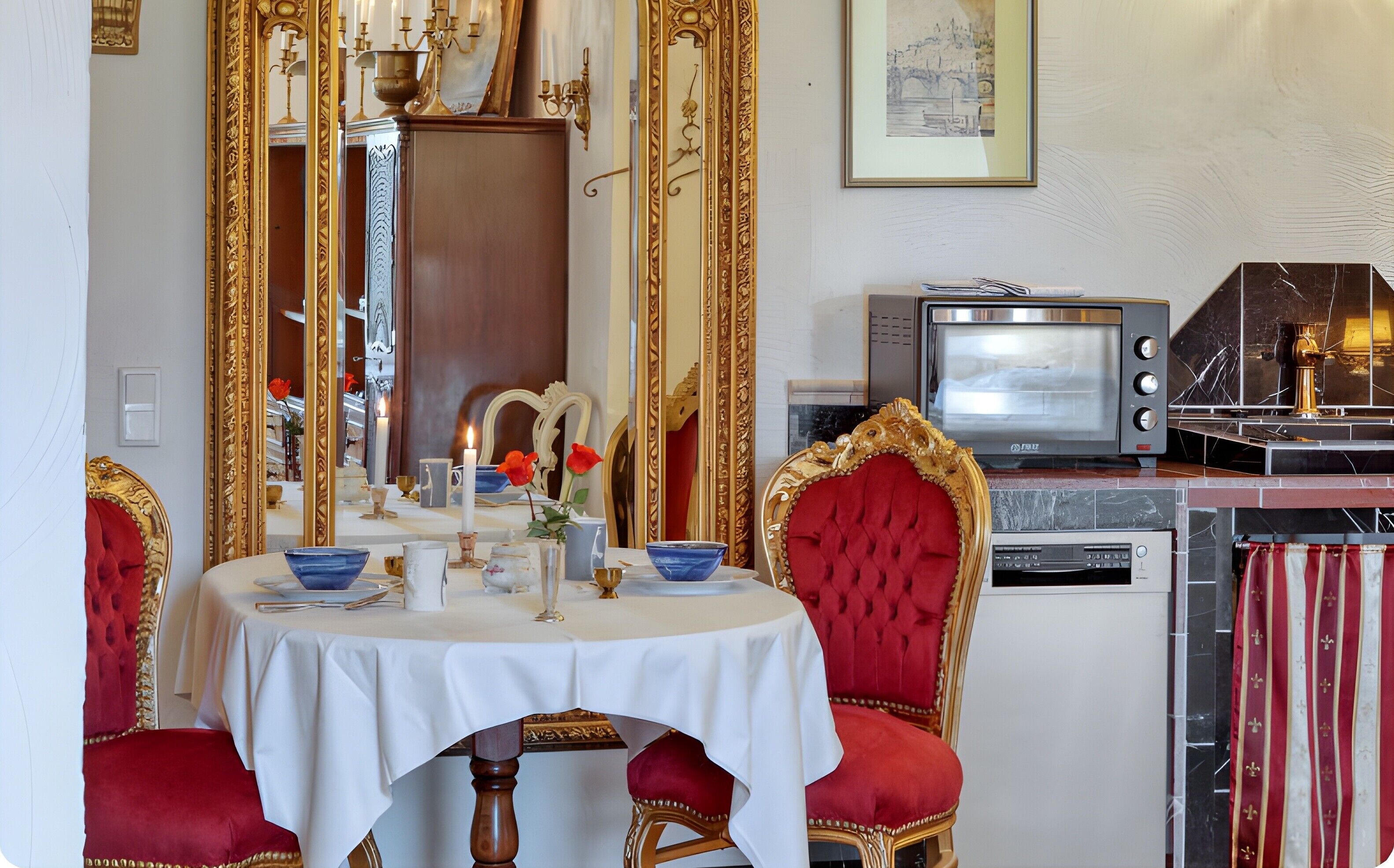 A dining area with a round table, red upholstered chairs, a gold-framed mirror, and a vintage television.