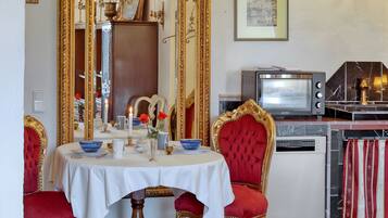 A dining area with a round table, red upholstered chairs, a gold-framed mirror, and a vintage television.
