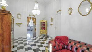 A room with a checkered floor, a red leather sofa, a chandelier, and ornate wall decorations.