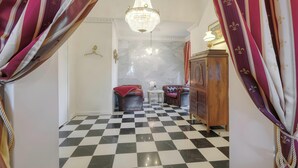 A checkered floor, a chandelier, a wooden cabinet, and red curtains.