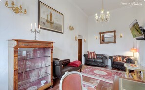 A living room with a fireplace, a chandelier, a sofa, and a dining table. - Apartment 'Panorama Suite' with Shared Garden and Wi-Fi (Emmelsbüll-Horsbüll)