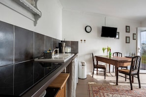 A kitchen with a black stove, white sink, and a dining area with a wooden table and chairs.