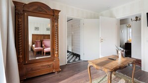 A room with a large mirror, a wooden table, a chair, and a checkered floor.