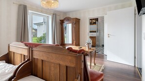 A bedroom with a wooden bed, a chandelier, a large mirror, and a view of the outside.