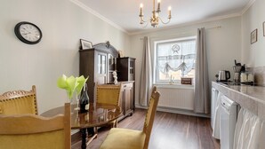A dining area with a round table, chairs, a clock, and a chandelier.