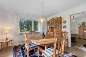 Ein Esszimmer mit Holztisch, Stühlen, einem Schrank und einem Fenster.