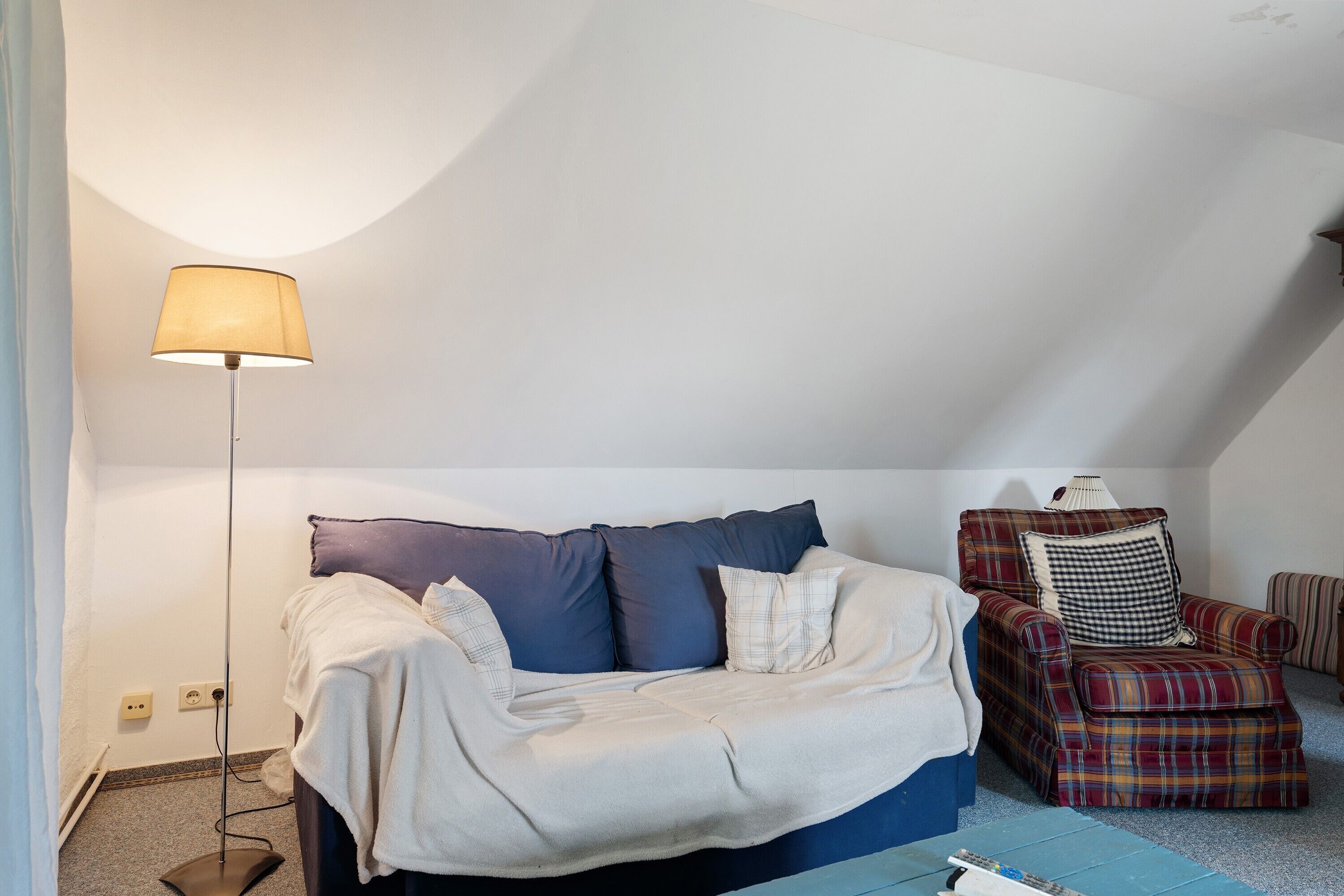 A bedroom with a bed, a chair, a lamp, and a carpeted floor.