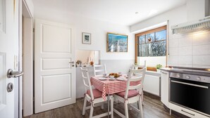 A kitchen with white cabinetry, a stove, and a dining table with chairs. - Apartment 'Ferienwohnung Lemburg' with Shared Terrace, Shared Garden and Wi-Fi (Nindorf)