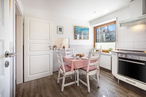 Una cocina con armarios blancos, una estufa y una mesa de comedor con sillas.