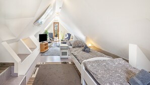 A bedroom with a sloped ceiling, a bed, a desk, a chair, and a TV. - Apartment 'Ferienwohnung Lemburg' with Shared Terrace, Shared Garden and Wi-Fi (Nindorf)