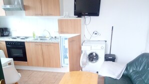 Un espacio habitable compacto con kitchenette, zona de comedor y zona de estar.