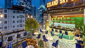 A rooftop bar with a view of city buildings, featuring outdoor seating and a bar area. - 22Land Hotel Saigon (Ho Chi Minh City)