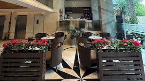 A modern hotel lobby with a geometric black and white floor pattern, a central chandelier, and potted plants with red flowers. - 22Land Hotel Saigon (Ho Chi Minh City)