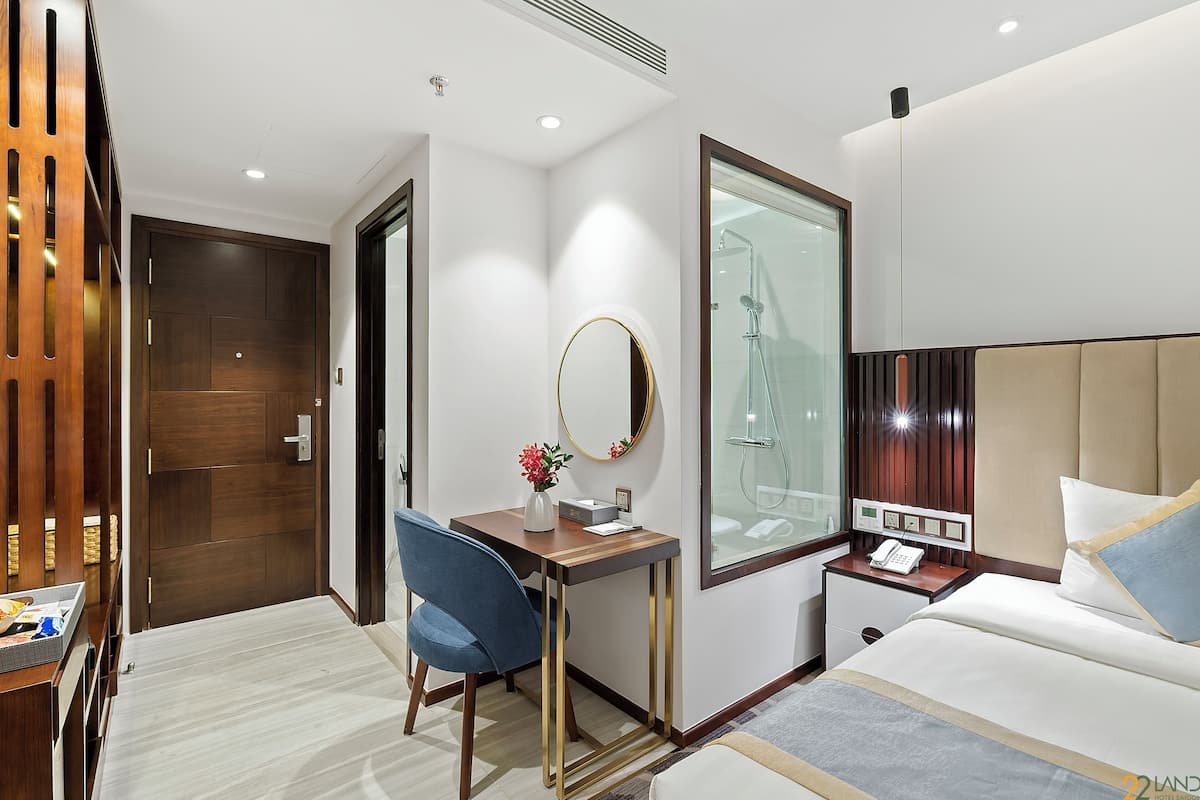 Une chambre d’hôtel équipée d’un lit, d’un bureau, d’une chaise, d’un miroir, d’une table de chevet et d’une armoire.
