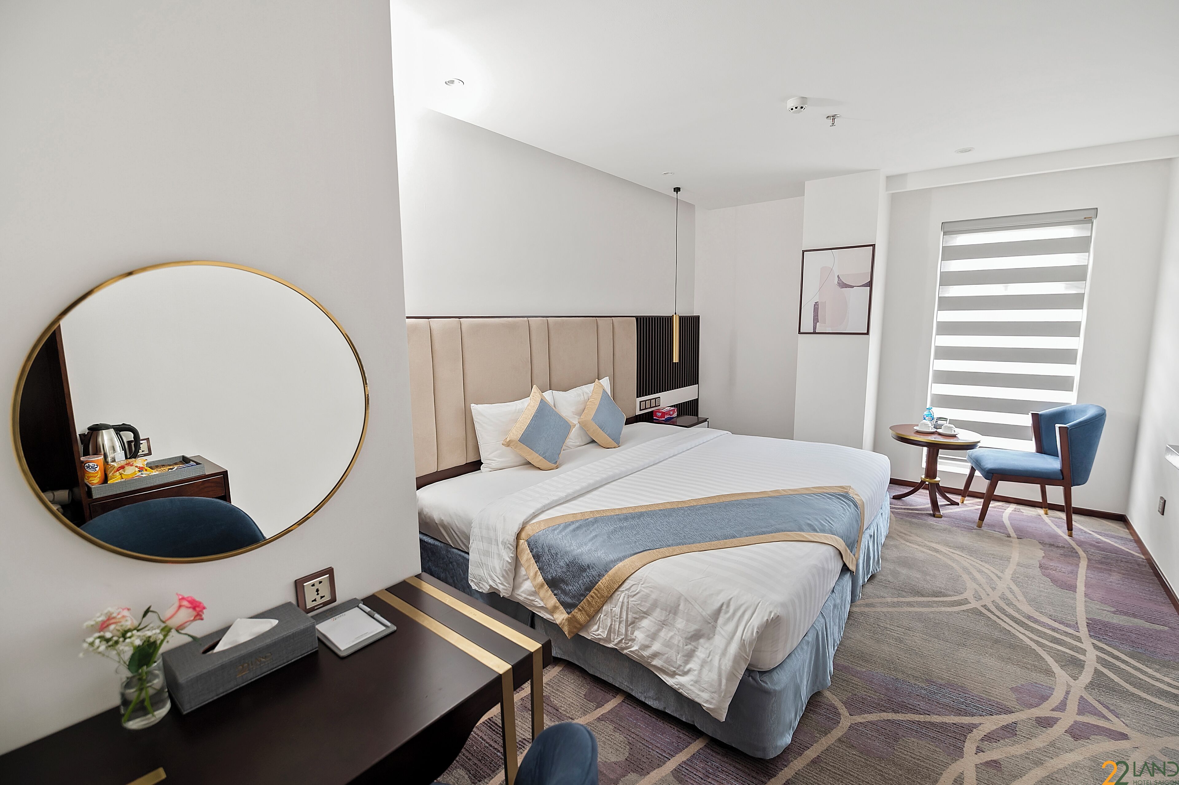 Une chambre d’hôtel avec un grand lit, une table de chevet, une chaise et un miroir.