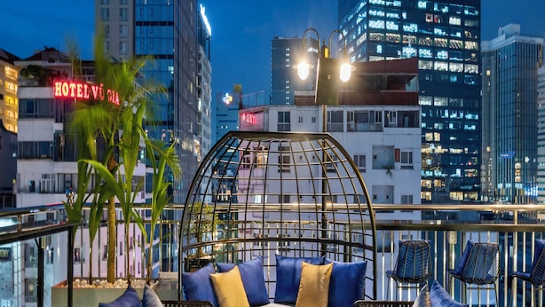 A rooftop lounge with a glass dome seating area, a potted plant, and a view of the city skyline at dusk. - 22Land Hotel Saigon (Ho Chi Minh City)