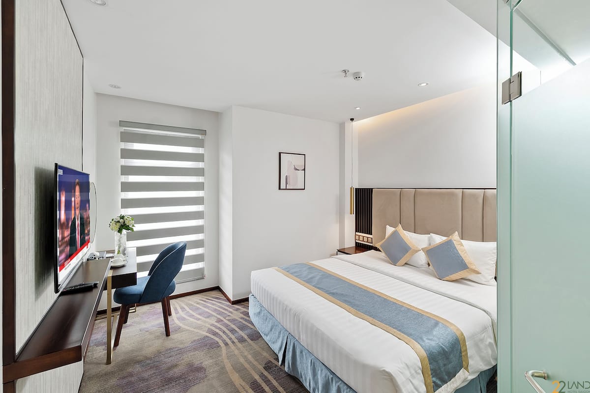 Une chambre d’hôtel moderne avec un grand lit, un bureau avec une télévision et une chaise.