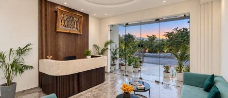 A reception area with a wooden reception desk, a large window with a view of the street, and two sofas.