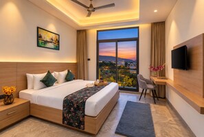A modern hotel room with a large bed, a desk, a flat-screen TV, and a balcony with a city view. - 7 Rays Hotel (Udaipur)