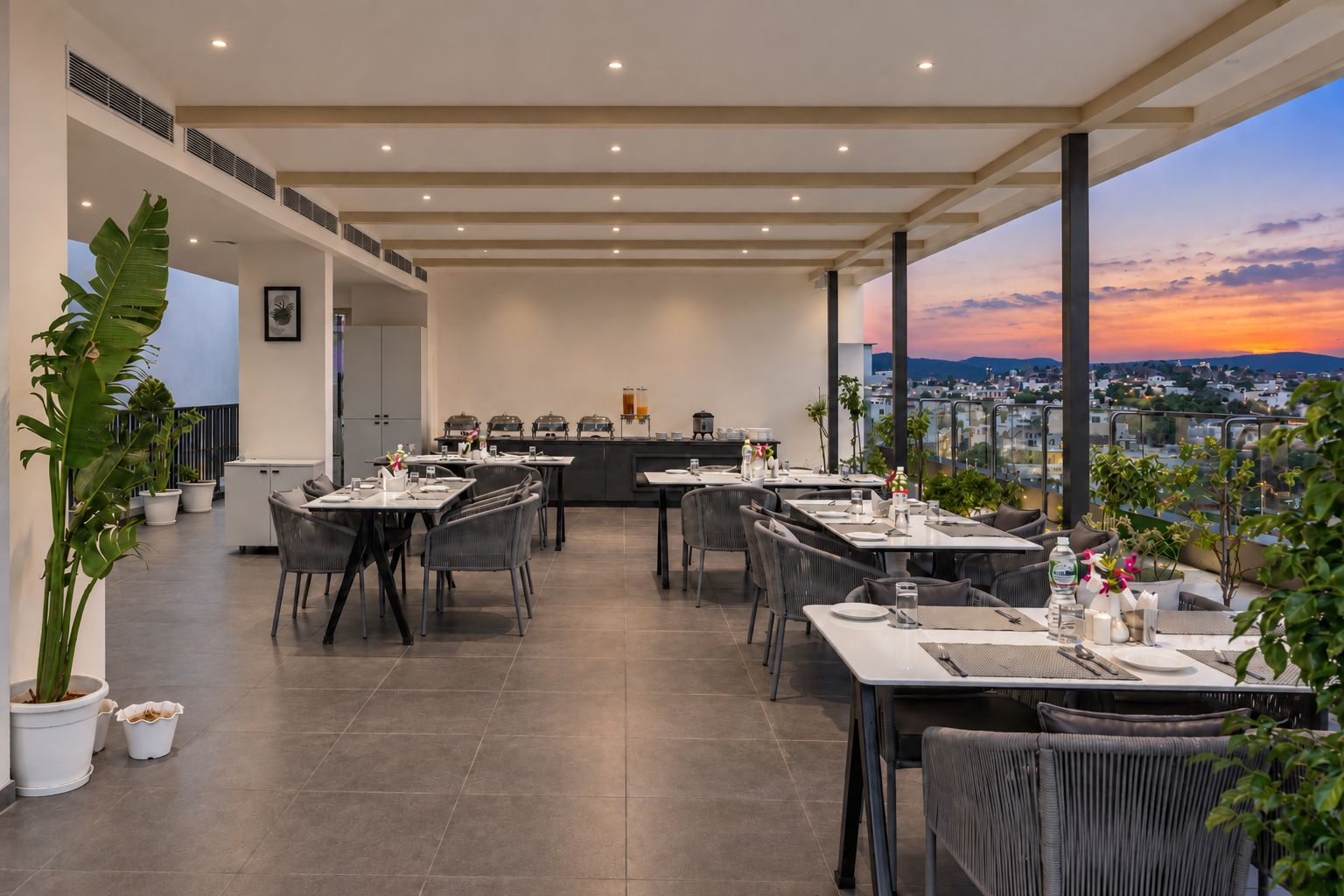 Een restaurant met terras, uitzicht op de stad en een zonsondergang.