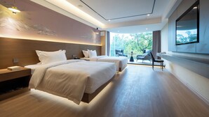 Habitación de hotel moderna con dos camas, un televisor grande y vistas al exterior.