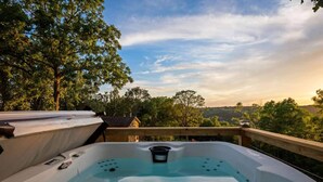 Un jacuzzi en una terraza de madera con una vista panorámica de árboles y colinas.