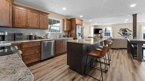 Una cocina amplia con armarios de madera, electrodomésticos de acero inoxidable y una isla central con taburetes de bar.