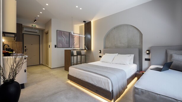 A modern hotel room with a large bed, a desk, and a dining area. - Loena Luxury Suites (Thessaloniki)
