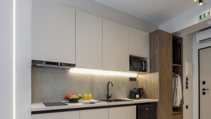 A modern kitchen with white cabinets, a built-in microwave, a coffee maker, and a sink. - Loena Luxury Suites (Thessaloniki)