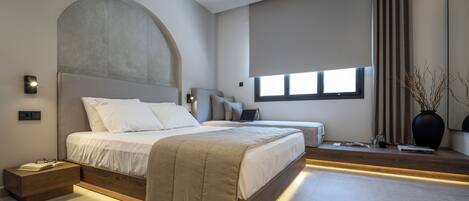A modern bedroom with a large bed, bedside tables, a nightstand, and a window with curtains.