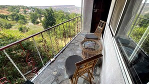 A balcony with wicker furniture and a view of a green landscape.
