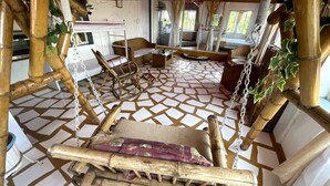 A room with a bamboo swing, cushioned seating, and a patterned floor.