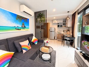 A modern living room with a grey sofa, a coffee table, and a vibrant painting of a beach scene.