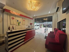 A reception area with a red and white counter, a chandelier, and a red sofa. - Golden Star Pattaya (Pattaya)