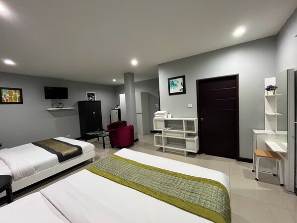A hotel room with two beds, a desk, a chair, a wardrobe, a TV, and a door.