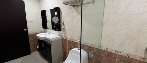 A modern bathroom with a toilet, sink, and glass shower enclosure.