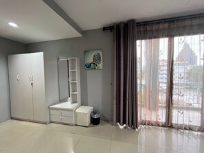 A room with a wardrobe, a bench, a trash bin, and a window with curtains. - Golden Star Pattaya (Pattaya)