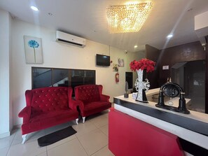 A modern living room with a red sofa, a white coffee table, and a decorative vase with red flowers. - Golden Star Pattaya (Pattaya)